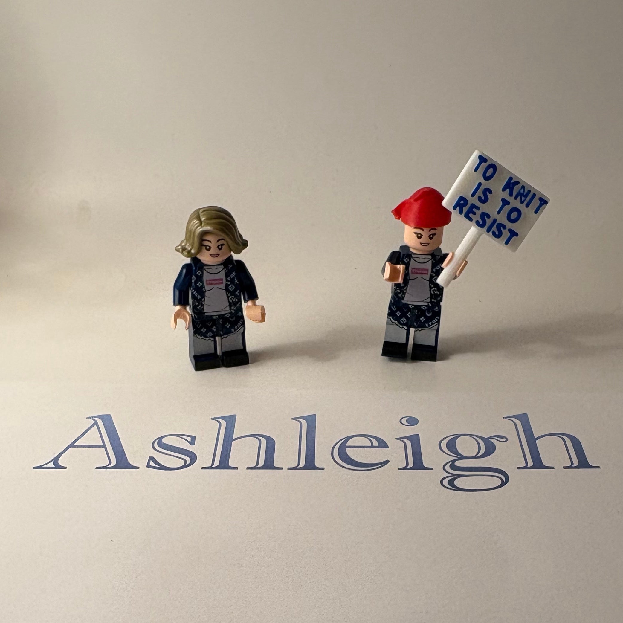 Two small figurines on a surface with 'Ashleigh' written above them.